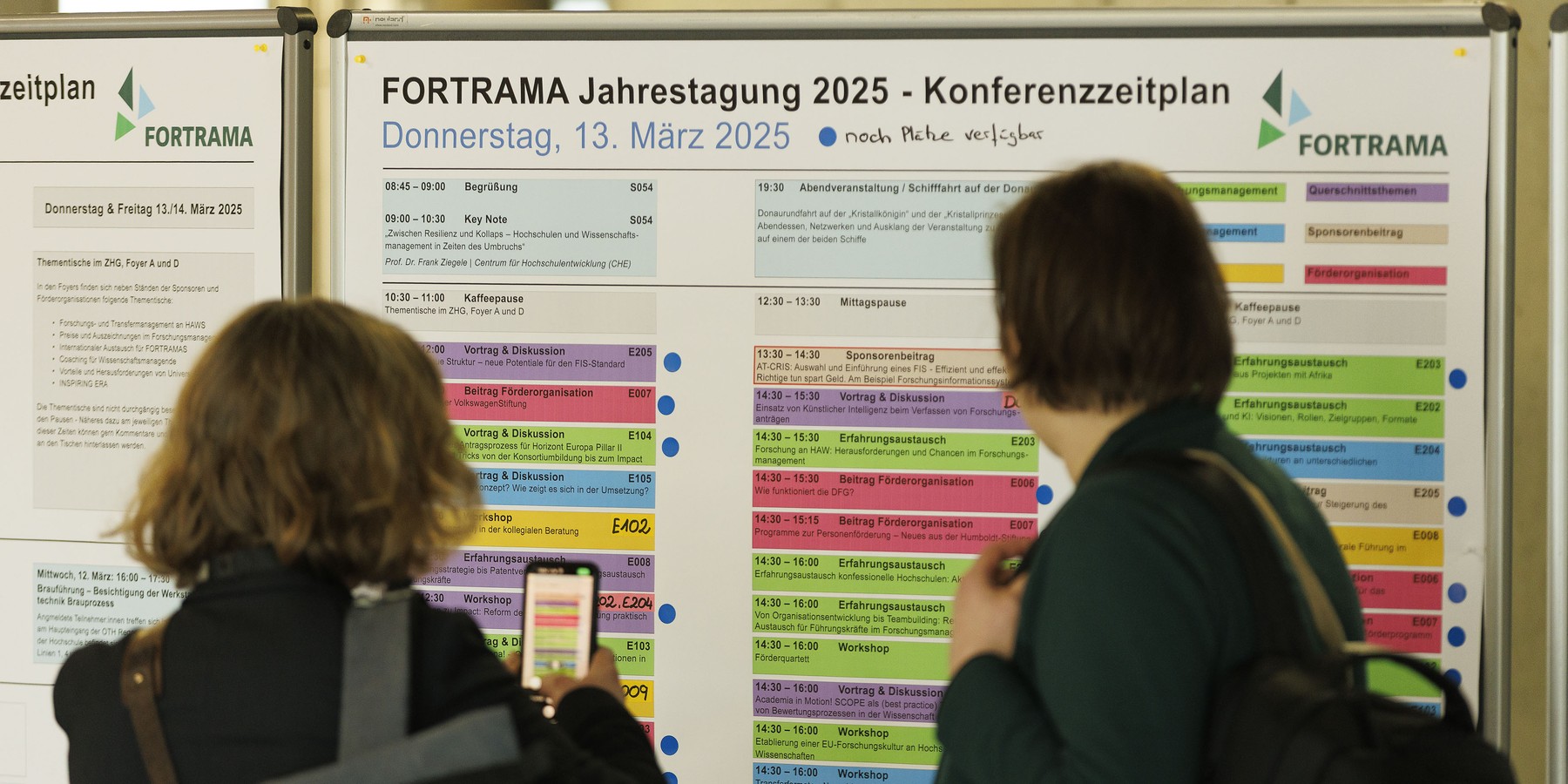 Zwei Personen vor einem Tagungsprogramm