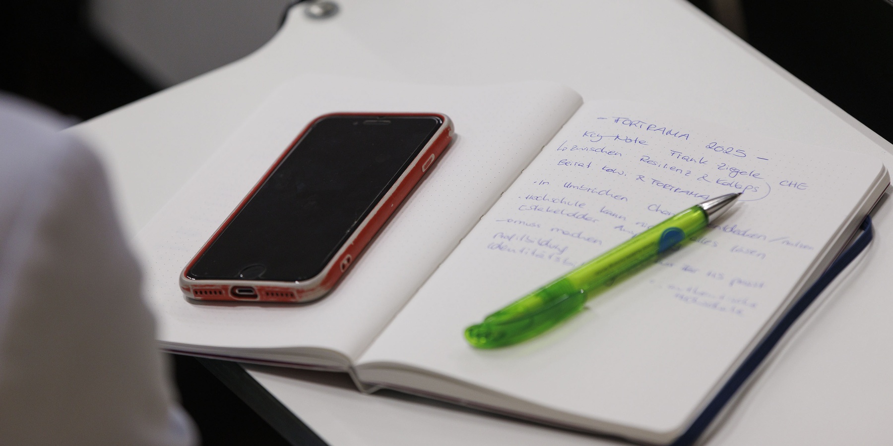 Smartphone und Stift auf einem Schreibblock