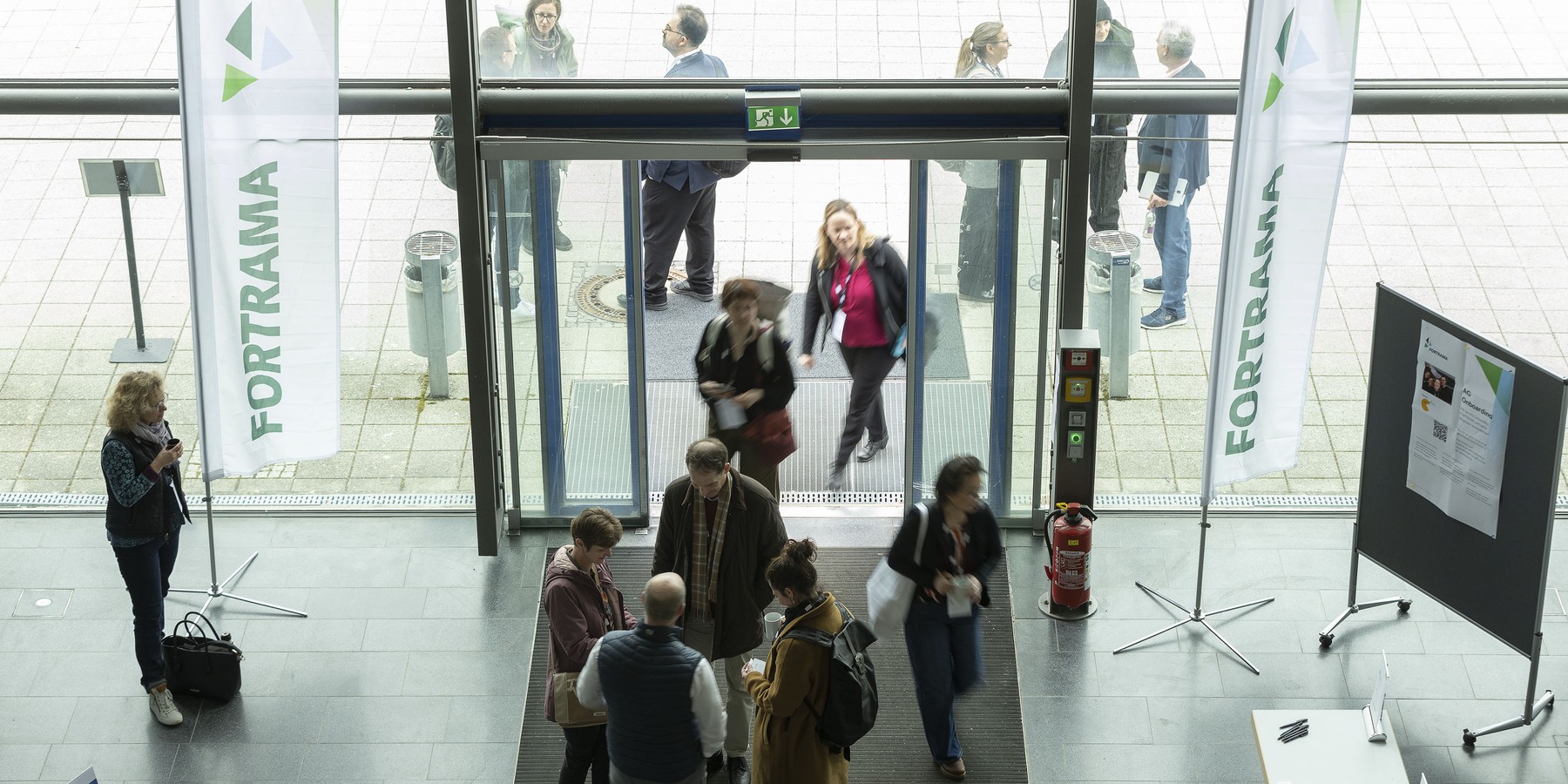 Tagungsbesucher passieren eine Glastür
