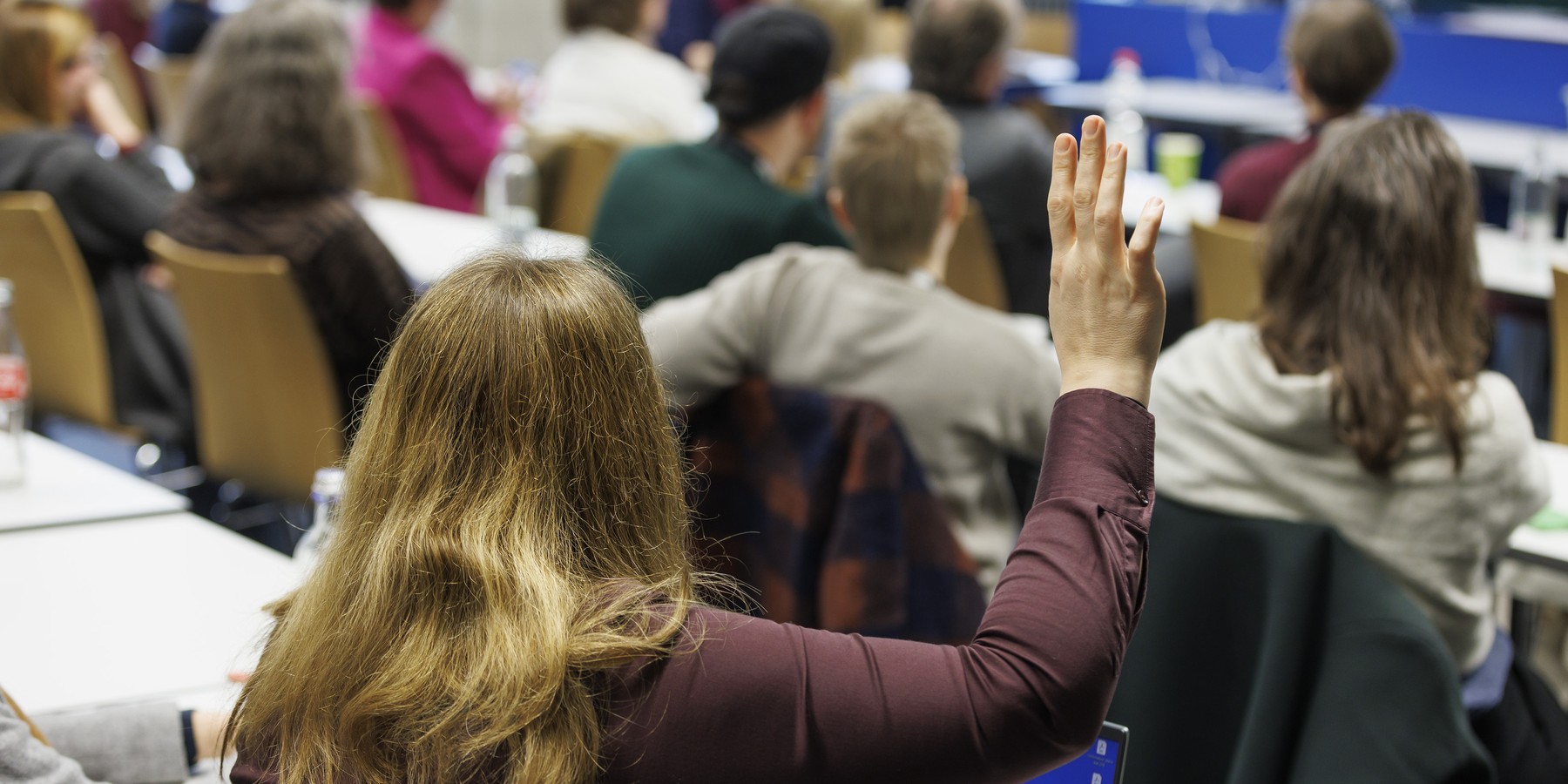 Frau im Hörsaal hebt die Hand